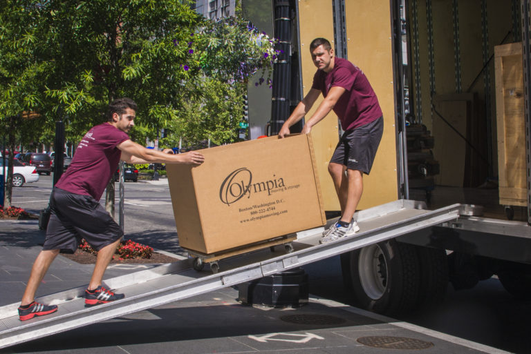 Two Olympia movers rolling a box onto a truck